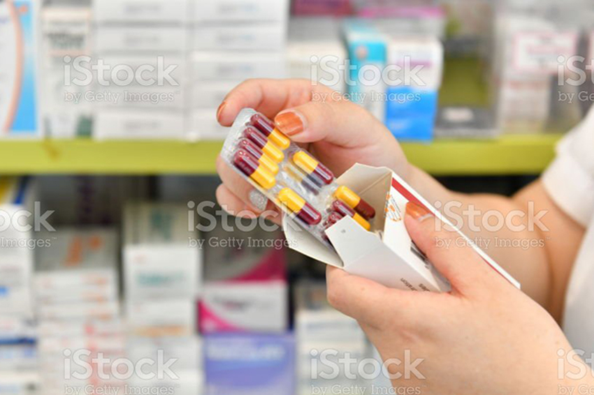 Hand holding medicine capsule pack at the pharmacy drugstore.